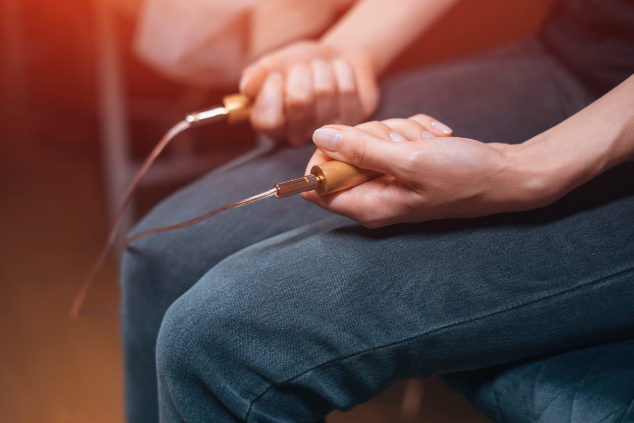 Séance de biorésonance : électrodes tenues en main, reliées à l’appareil de mesure